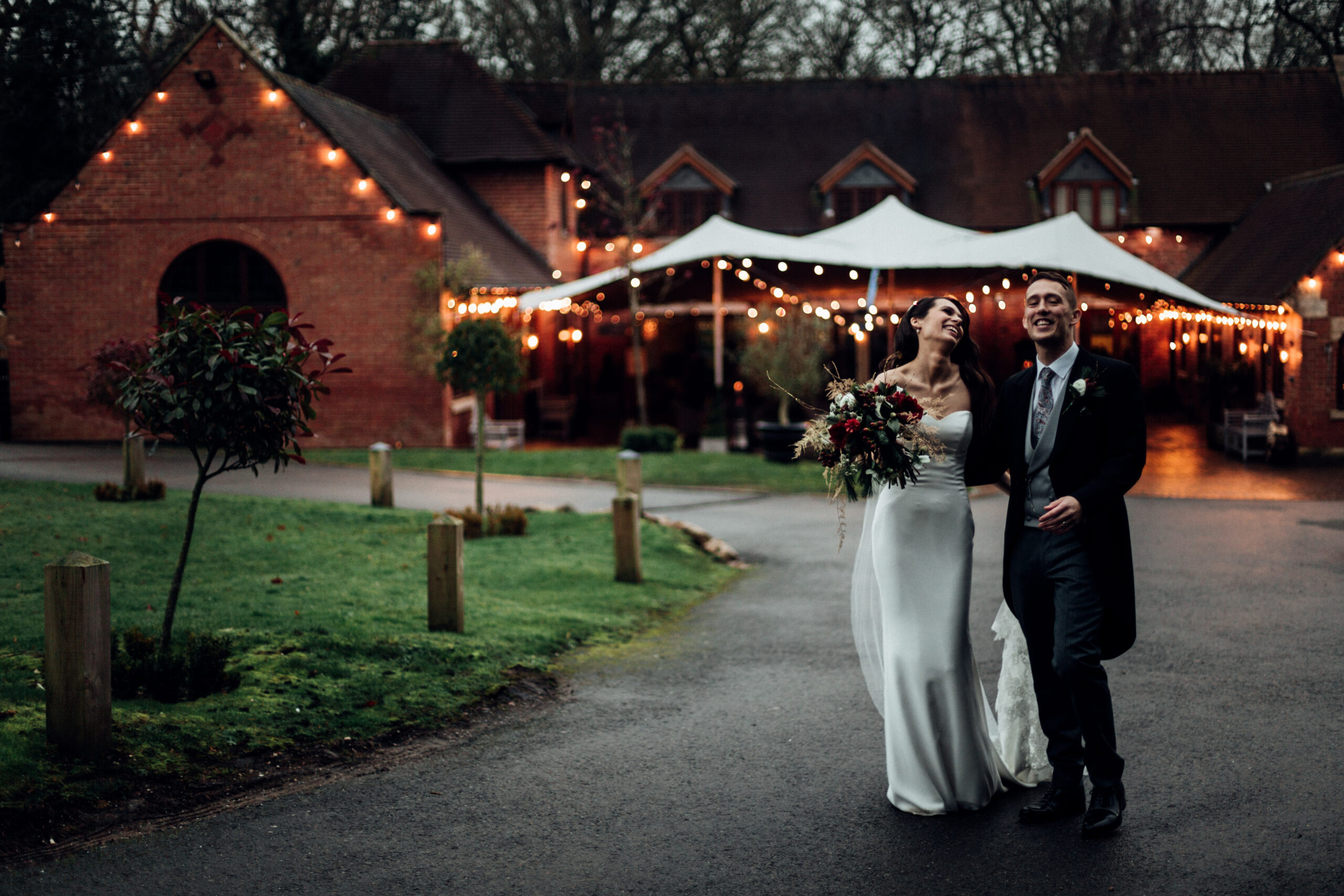 Laughing wedding couple outside the Stables barn at Nuthurst Hotel