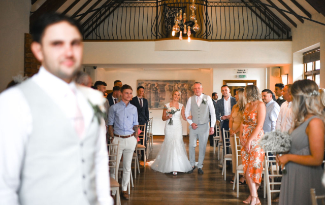 Bride is walking down the aisle with her father at Nuthurst Grange Hotel